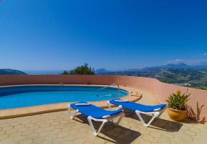 - une piscine avec deux chaises bleues à côté dans l'établissement Villa Linda Vista - stunning views - by Holiday Rentals Villamar, à Benitachell