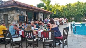 a group of people sitting at a table by a pool at Doga Apartments in Kayakoy