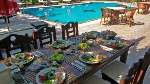 a table with plates of food next to a swimming pool at Doga Apartments in Kayakoy