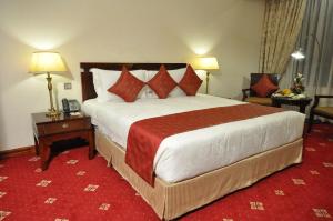 una habitación de hotel con una cama grande y una alfombra roja en Weston Hotel, en Nairobi