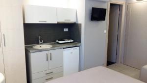 a small white kitchen with a sink and a tv at Il Mondo Residence in Stavros