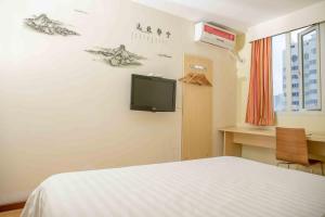 - une chambre avec un lit et une télévision murale dans l'établissement 7Days Inn Huizhou West Lake, à Huizhou