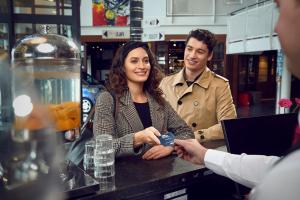 un hombre entregando a una mujer un celular en un bar en WestCord Art Hotel Amsterdam 4 stars, en Ámsterdam