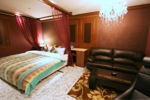 a bedroom with a bed and a black leather chair at Sari Resort Daito (Adult only) in Daitō