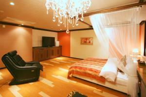 a bedroom with a bed and a chair and a chandelier at Sari Resort Daito (Adult only) in Daitō