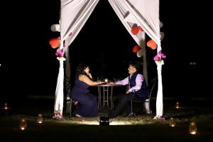 um homem e uma mulher sentados numa mesa debaixo de uma tenda em Savana Lake Resort em Nashik