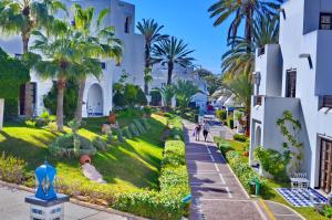 un jardin en face d'un bâtiment avec des palmiers dans l'établissement El Pueblo Tamlelt, à Agadir