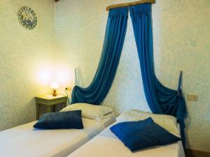 two beds in a bedroom with blue drapes at Belvilla by OYO Nice Farmhouse with Sauna Jacuzzi in Pieve a Nievole