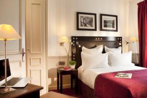 a hotel room with a bed and a desk with a laptop at Hotel Duquesne Eiffel in Paris