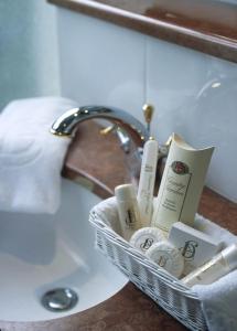 uma cesta de produtos de higiene pessoal ao lado de um lavatório em Hotel Duquesne Eiffel em Paris