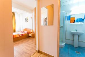 a bathroom with a shower and a sink and a bed at Hostel Horia in Plopeni