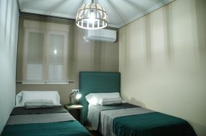 Cette petite chambre comprend deux lits et un lustre. dans l'établissement Alcazar de Baeza Centro Godoyes, à Baeza