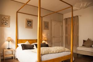 a bedroom with a canopy bed with white sheets and pillows at Les Chambres de Lourmel in Pontivy