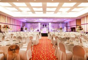 a wedding banquet hall with white tables and chairs at Ramada Hotel & Suites by Wyndham Ajman in Ajman  +37 photos