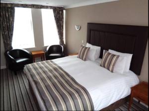 a hotel room with a bed, chair, and nightstand at Aston Court Hotel in Derby