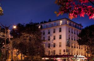 a large white building at night with a street light at Hotel Duquesne Eiffel in Paris