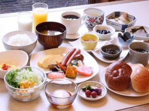 une table avec des assiettes et des bols de nourriture dans l'établissement APA Hotel Takaoka-Marunouchi, à Takaoka