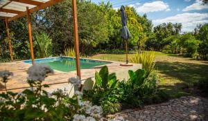 a swimming pool with an umbrella in a garden at Rouana Guest Farm in Stellenbosch