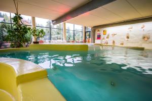 a swimming pool in a building with a large window at Hotel Čingov Slovenský raj in Smižany