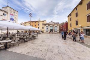 a group of people walking down a street with tables and chairs at Globe Apartament 2 in Zadar