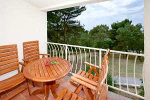 a balcony with a wooden table and two chairs at Apartments Bellevue Plava Laguna in Poreč