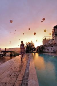 une personne se promenant à côté d'une piscine avec des montgolfières dans l'établissement Kelebek Special Cave Hotel & Spa, à Gorëme