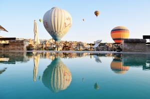 three hot air balloons flying over a pool of water at Kelebek Cave Hotel in Göreme +272 photos