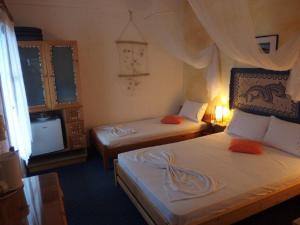 ein Hotelzimmer mit 2 Betten und einem TV in der Unterkunft Pension Titika in Katápola