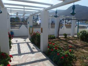 a white pergola with red flowers in a yard at Pension Titika in Katapola