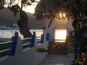 a house on the beach with a tree in the foreground at Pension Titika in Katapola