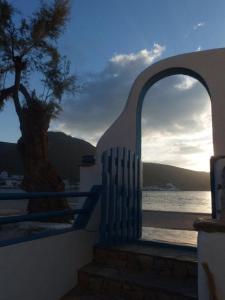 a view of the ocean through an archway with a tree at Pension Titika in Katapola