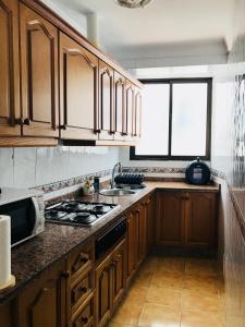 cocina con armarios de madera y horno con fogones en Casa Rural Setenil, en Setenil