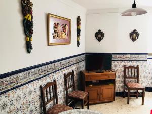sala de estar con TV y sillas en Casa Rural Setenil, en Setenil