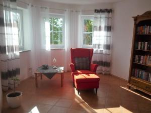 ein Wohnzimmer mit einem roten Stuhl und einem Tisch in der Unterkunft "Villa Sabine" in Waidhaus