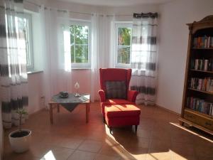 a living room with a red chair and a table at "Villa Sabine" in Waidhaus