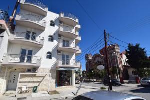 a white building on a street next to a building at KyMa Studios and Suites in Asprovalta
