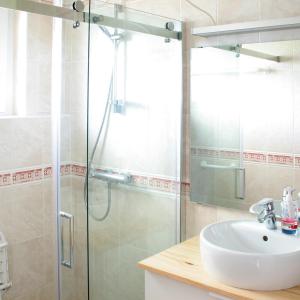 La salle de bains est pourvue d'un lavabo et d'une douche en verre. dans l'établissement Ranch Bignaou, à Amou