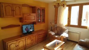 a living room with a tv and a chair and a couch at Apartamento en Sallent de Gallego in Sallent de Gállego