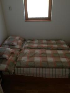 a bed in a small room with a window at Guliba Vendégház in Bogács