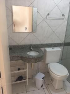 y baño con aseo, lavabo y espejo. en Apartamento San Lorenzo, en Maceió