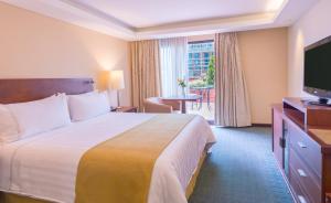 um quarto de hotel com uma cama grande e uma televisão em GHL Hotel Capital em Bogotá