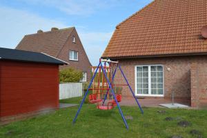 un parque infantil en el patio de una casa en Deichperle Nessmersiel, en Nessmersiel