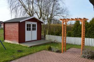 ネスマージールにあるDeichperle Nessmersielの庭の白い扉付き赤小屋
