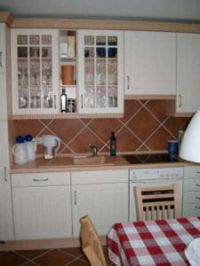 ネスマージールにあるDeichperle Nessmersielのキッチン(シンク、白いキャビネット、テーブル付)