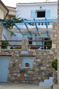 a house with a stone wall and a blue pergola at Stella's traditional house. in Alonnisos