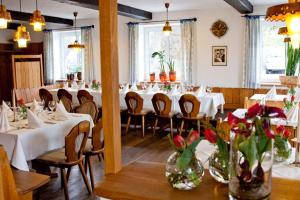 a restaurant with white tables and chairs and flowers at Hotel Wirtshaus am Schloss in Aicha vorm Wald