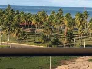 a view of the beach and palm trees from a window at Victory Flat Intermares in Cabedelo