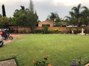a yard with a large lawn in front of a house at Sunrise Boutique Hotel in eMalahleni