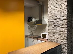 a kitchen with a stone wall and a microwave at Apartamentos Arquitas in Mérida