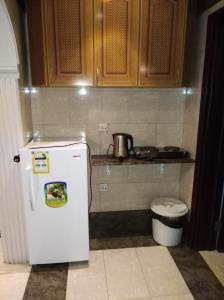 a kitchen with a white refrigerator and a toilet at Mkani Apartment in Al Khobar